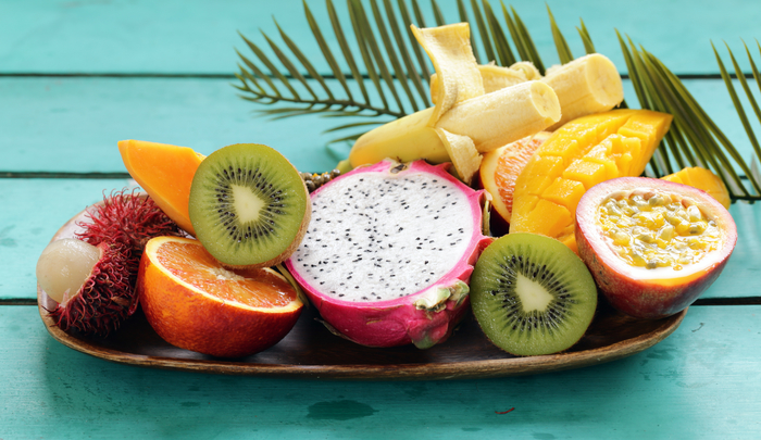 Verschiedene frische tropische Früchte. Rambutan, Papaya, Kiwi, Mango auf einem hölzernen Hintergrund