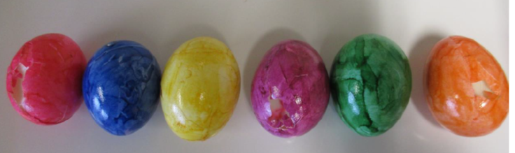 In einer Reihe liegen bunte Eier, die unterschiedliche Defekte an der Schale haben