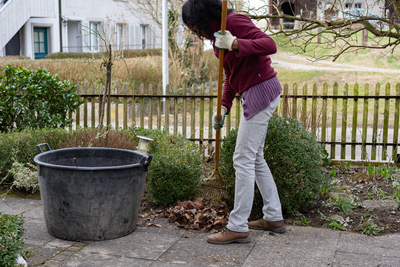 Eine Frau harkt Laub im Garten