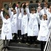 Schüler in weißen Kitteln winken