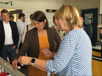 Ministerin Staudte schaut kritisch auf eine kleine Glasflasche in ihrer Hand. Eine LAVES-Mitarbeiterin steht neben ihr, hält ebenfalls ein Fläschen in der Hand und gibt Erklärungen. Das Ganze findet in einem Labor statt.