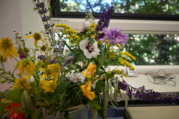 Ein bunter Strauß aus Feldblumen steht in einer hohen Vase.