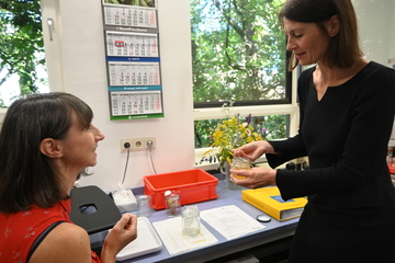Verbraucherschutzministerin Miriam Staudte steht Selina Campbell des LAVES Institut für Bienenkunde Celle gegenüber und hebt mit einem Stäbchen Honig aus einem kleinen Glas.