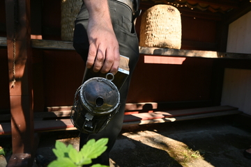 Eine schwarze Kanne mit einer Öffnung am Deckel wartet auf ihren Einsatz am Bienenstock.