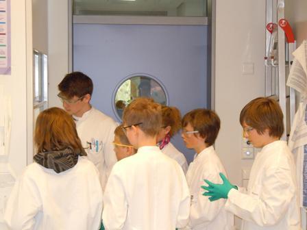 Schüler in weißen Kitteln im Labor