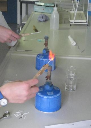 Hand hält Element über Flamme eines Bunsenbrenners