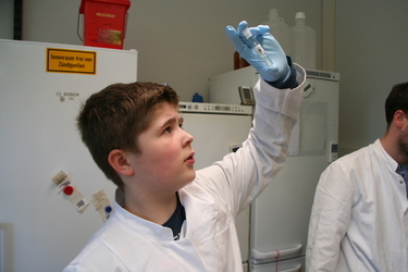 Ein Schüler hält ein Glas mit isolierter Tomaten-DNA