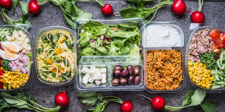 Auswahl an sauberen Diätsalaten in Plastikverpackung und grünem Maßband auf rustikalem Hintergrund, Draufsicht.