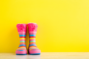 Bunte Gummistiefel vor gelbem Hintergrund