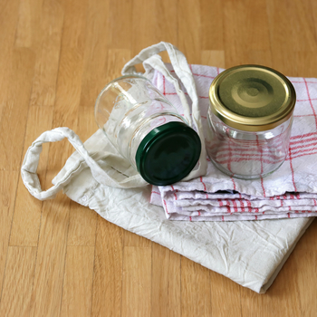 Eine Stofftasche, ein Geschirrtuch und zwei leere, saubere Gläser mit Schraubverschluss