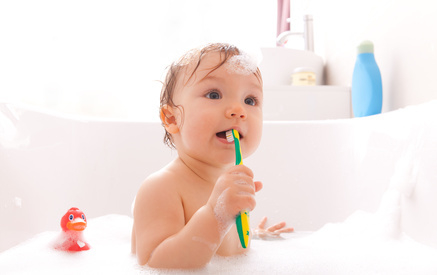Kleinkinder putzt Zähne in einer mit Badeschaum gefüllten Badewanne