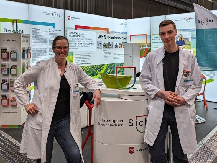 Dr. Juliane Krex und Marek Addicks stehen in weißen Laborkitteln am Stand des Landes Niedersachsen auf der VOCATIUM in Oldenburg.