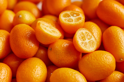 Kumquat Hälften liegen auf mehreren ganzen Kumquats.