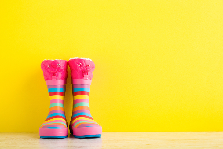 Bunte Gummistiefel für Kinder vor gelbem Hintergrund.