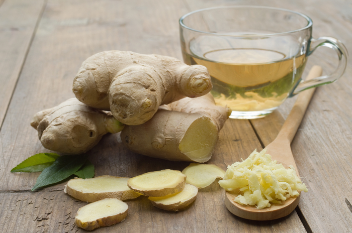 angeschnittene Ingwerknolle und Tasse mit frischem Ingwertee auf Holztisch