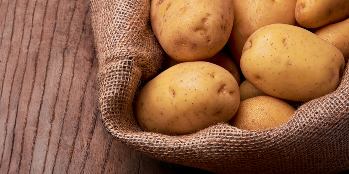 Kartoffeln in einem Jutesack auf einem Holztisch