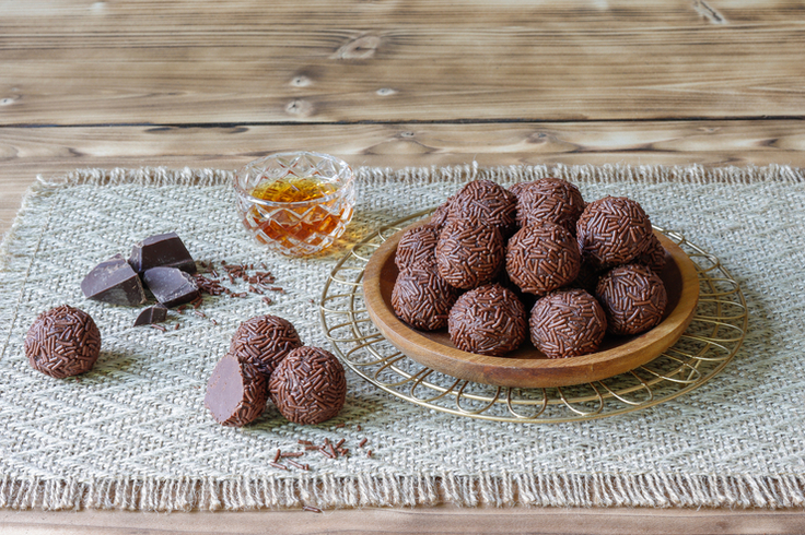 Rumkugeln auf einer Decke neben Glas mit Rum.