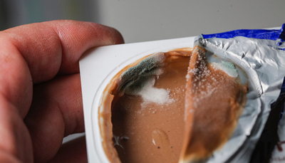 Nahaufnahme von Schimmel auf einem Becher Joghurt