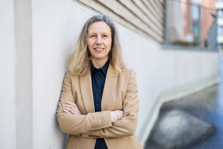 Dr. Andrea Luger lehnt an einer Wand.