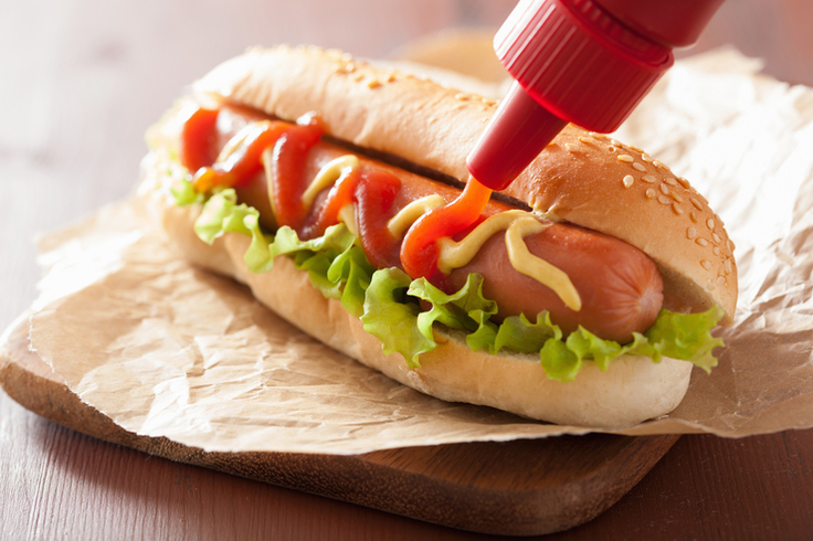 Würstchen im Hot-Dog-Brötchen mit Sesam zusammen mit Salat und Sauce