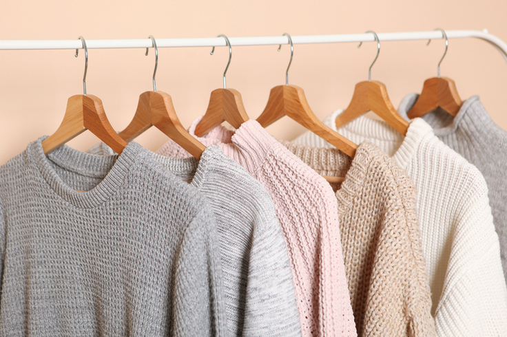 Pullover aus Wolle hängen auf Kleiderbügeln an einer Gaderobe.