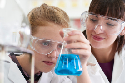 Auszubildende führt unter Anleitung Chemieexperimente durch