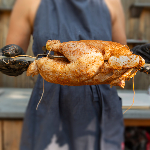 Ein rohes Grillhähnchen wurde mariniert und auf einen Grillspieß gesteckt.