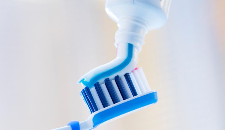 Nahaufnahme einer Zahnbürste und Zahnpasta auf verschwommenem Hintergrund