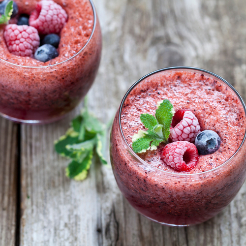 Smoothie im Glas mit gefrorenen Beeren obenauf.