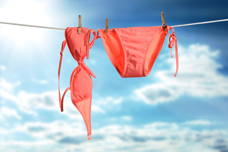 Ein roter Bikini auf einer Wäscheleine vor blauem Himmel.