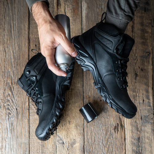 Trekkingschuhe werden mit Imprägnierspray eingesprüht.
