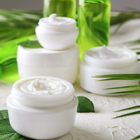 Glas mit Körpercreme auf weißem Tisch