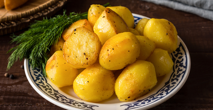 Goldbraun geröstete Kartoffeln auf einem Teller, garniert mit gemahlenem schwarzen Pfeffer und frischem Dill