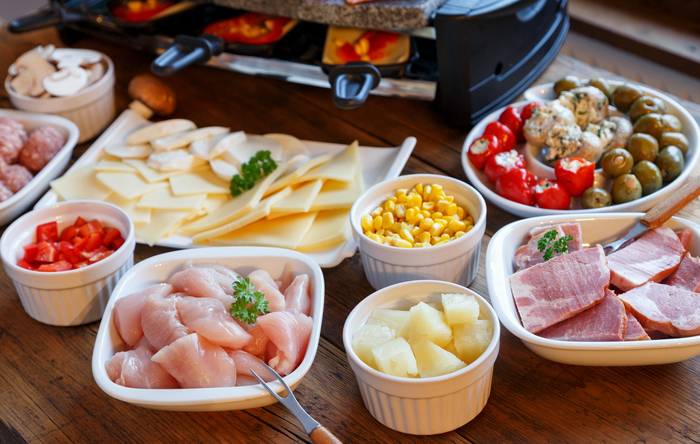 verschiedene Raclettezutaten in Schalen auf einem Tisch