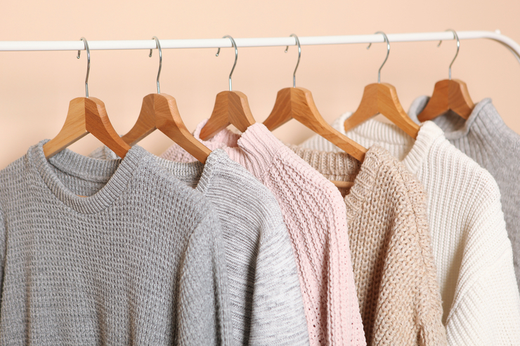 Pullover aus Wolle hängen auf Kleiderbügeln an einer Gaderobe.